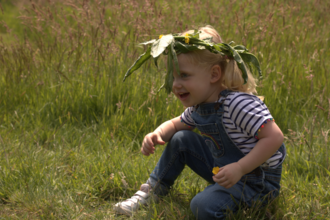 Young child playing in the grass with nature crown